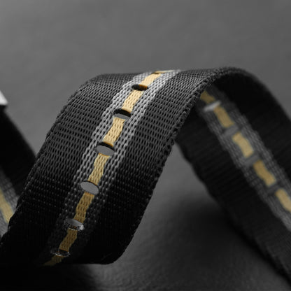Close-up of adjustment holes on black striped nylon NATO watch strap